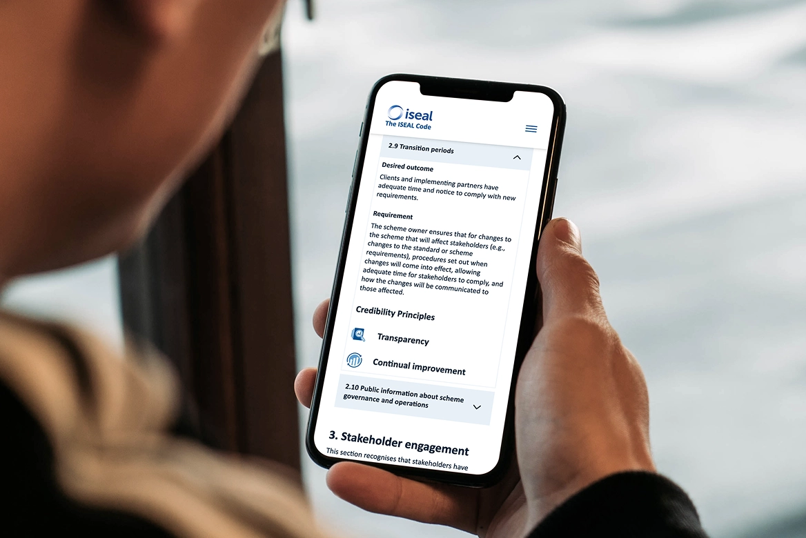 Person holding mobile phone with ISEAL website showing