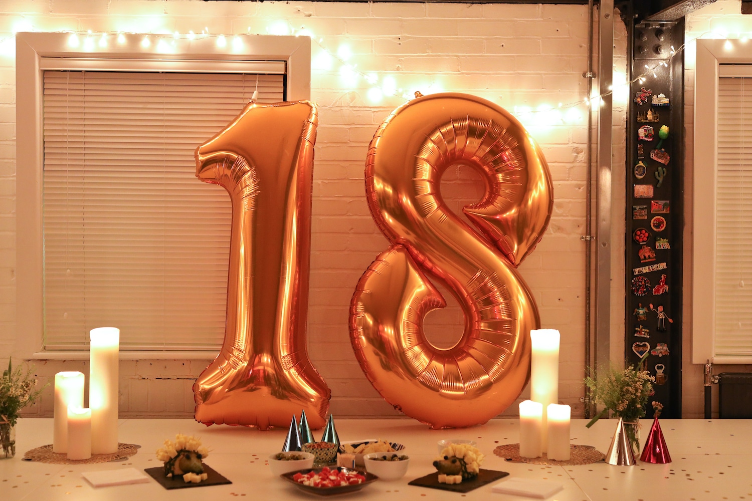Number 1 and number 8 Balloons on a table, surrounded by treats and candles.